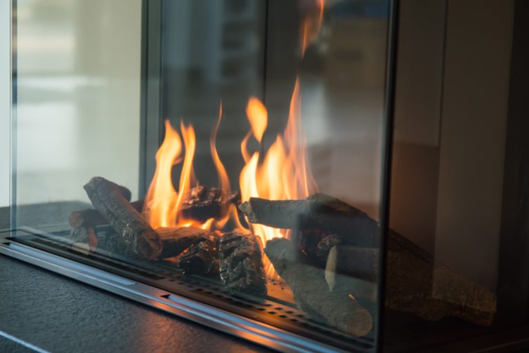 A fire burns in a glass fireplace, Broken Gas Fireplace Log - What To Do?