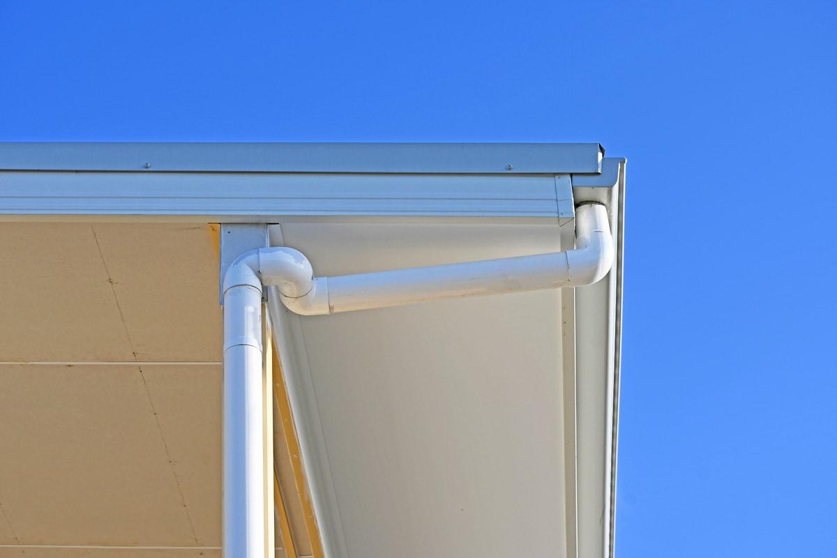 A white painted drain pipe on the house exterior
