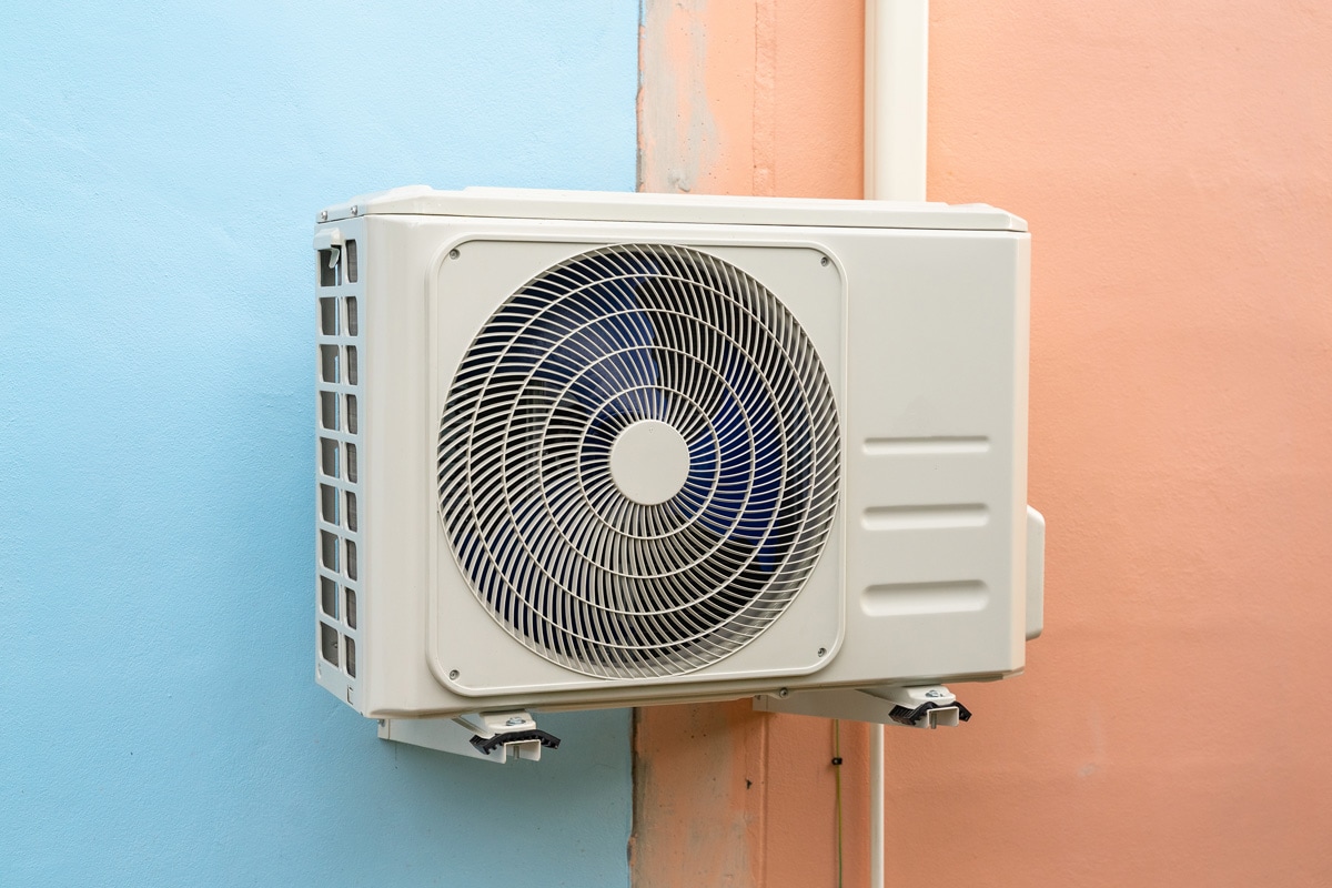 Air conditioning unit mounted on metal brackets outside a small building