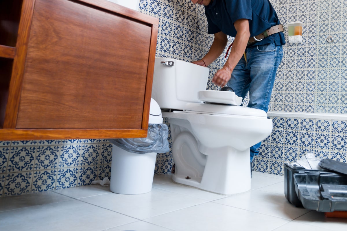 American plumber fixing a toilet in the bathroom