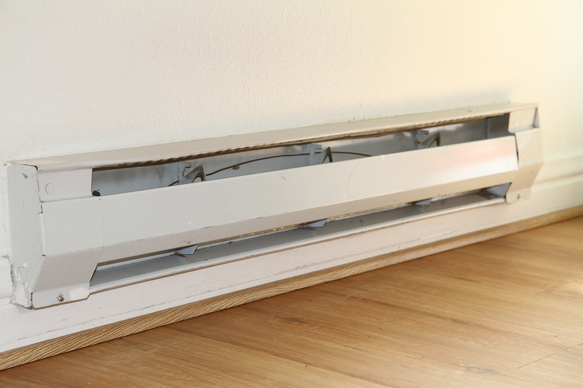 Baseboard heater on white wall and wood floor
