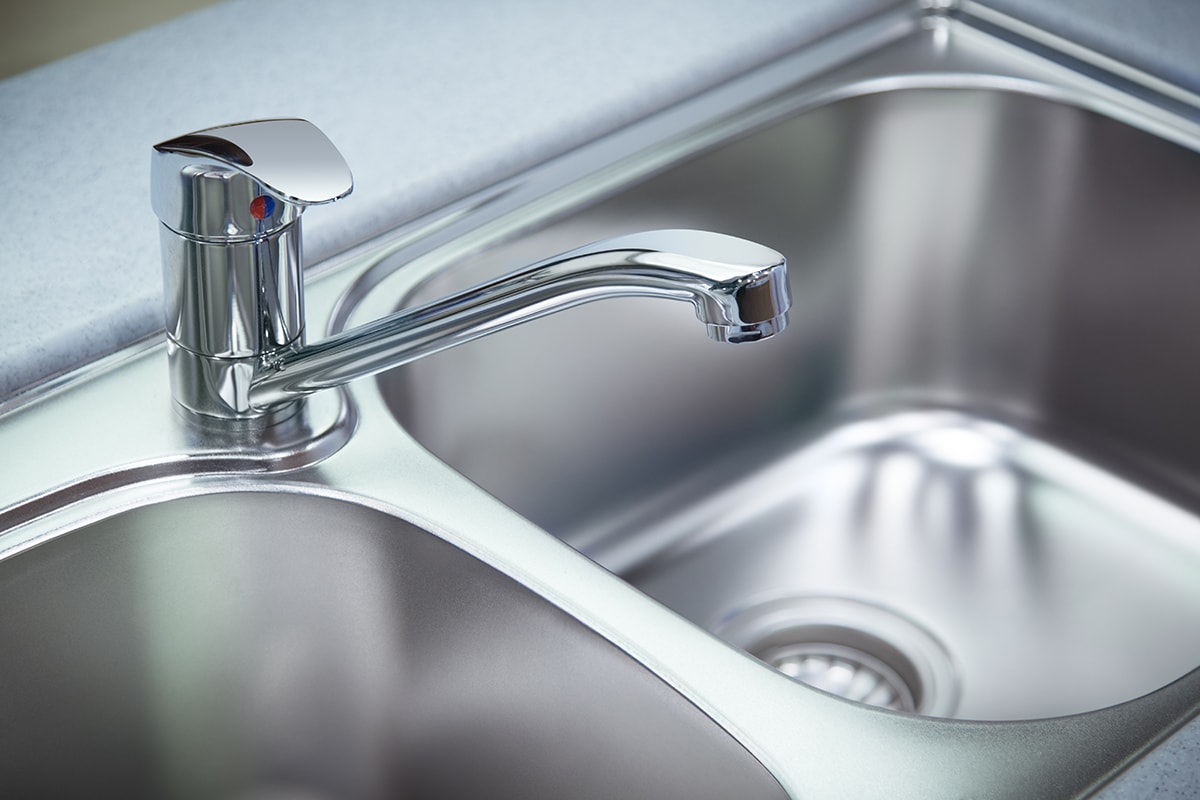 Clean chrome tap and washbasin in a kitchen