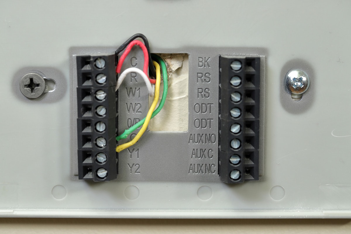 Close-up of thermostat wiring on wall, with colored wires