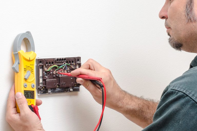 An HVAC technician testing voltage on a thermostat, How To Wire Mysa Thermostat