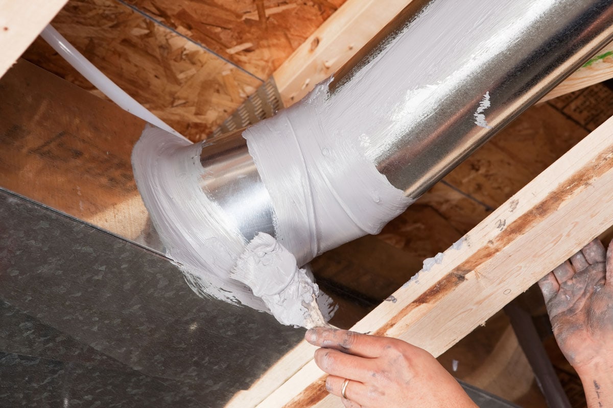Hand Sealing House Air Duct Joint with Caulk
