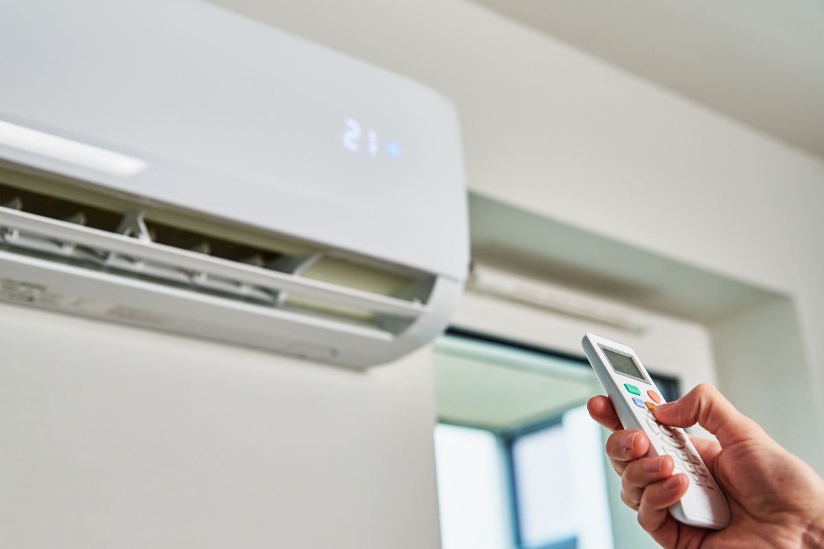 Hand adjusting temperature on air conditioner with remote control, Working air conditioner for comfort temperature in home at hot summerHand adjusting temperature on air conditioner with remote control, Working air conditioner for comfort temperature in home at hot summer