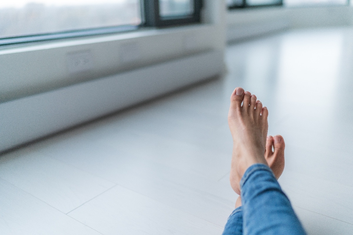 Where Would A Toe Kick Heater Be Installed? - Home relax comfort lifestyle woman barefoot relaxing at warm radiators heat system in apartment or condo living. Cozy winter electric baseboards in house. Closeup of feet.