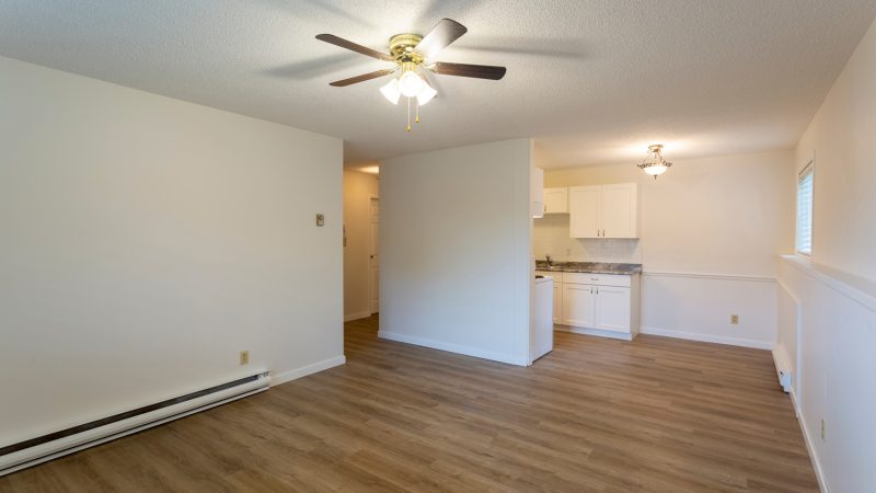 Interior of empty renovated apartment condo rental unit with white walls and new hard wood vinyl laminate flooring - Can You Have An Outlet Above A Baseboard Heater