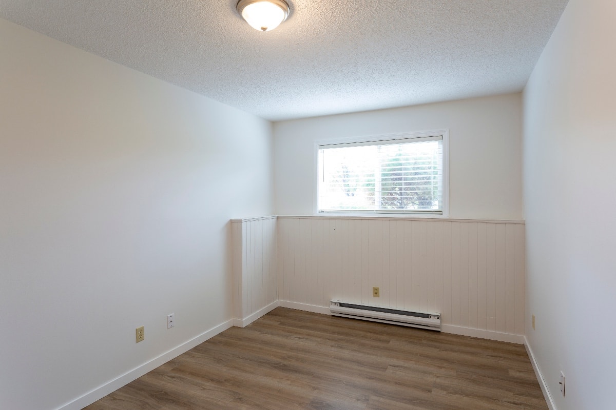 Interior of empty renovated apartment condo rental unit with white walls and new hard wood vinyl laminate flooring.