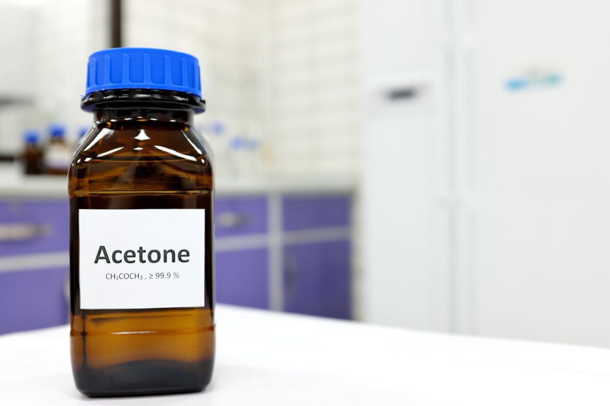 Selective focus of pure acetone solution in brown glass amber bottle inside a chemistry laboratory. White background with copy space.