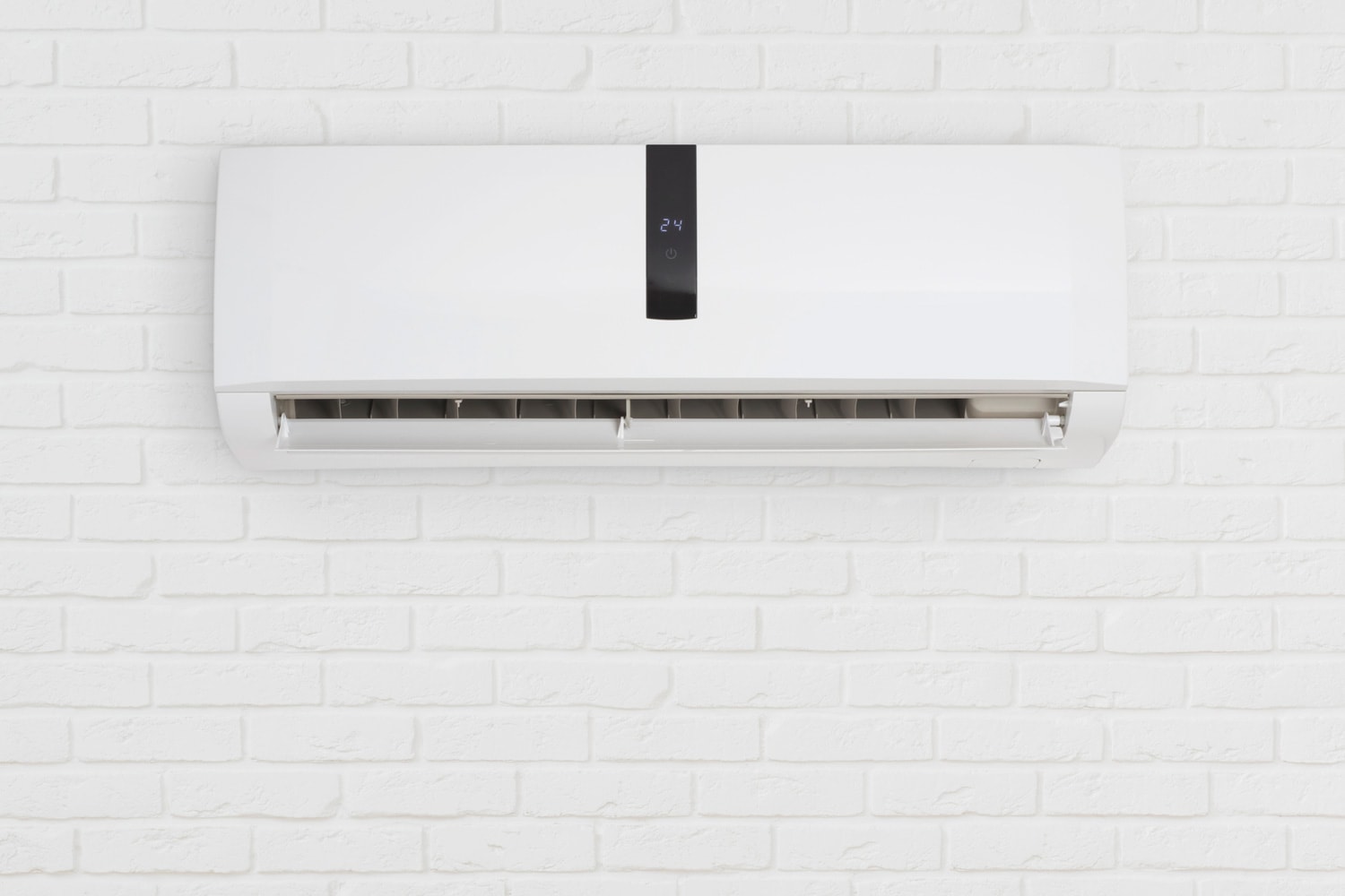 Split system air conditioning unit on decorative white brick wall