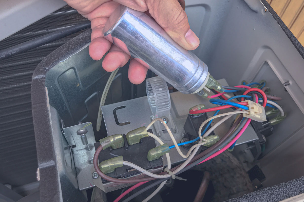The technician replace the capacity run of air conditioner while holding the capacitor