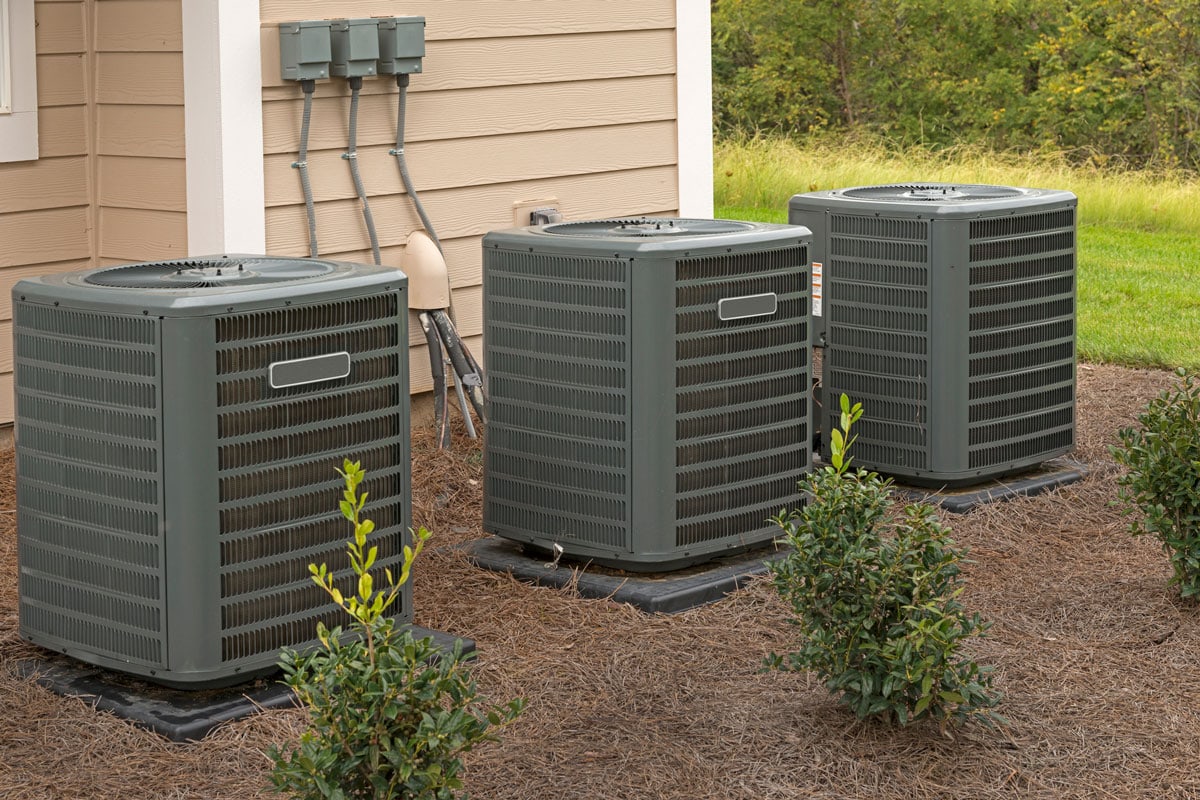 Three air conditioning units sit outside a recently constructed apartment building