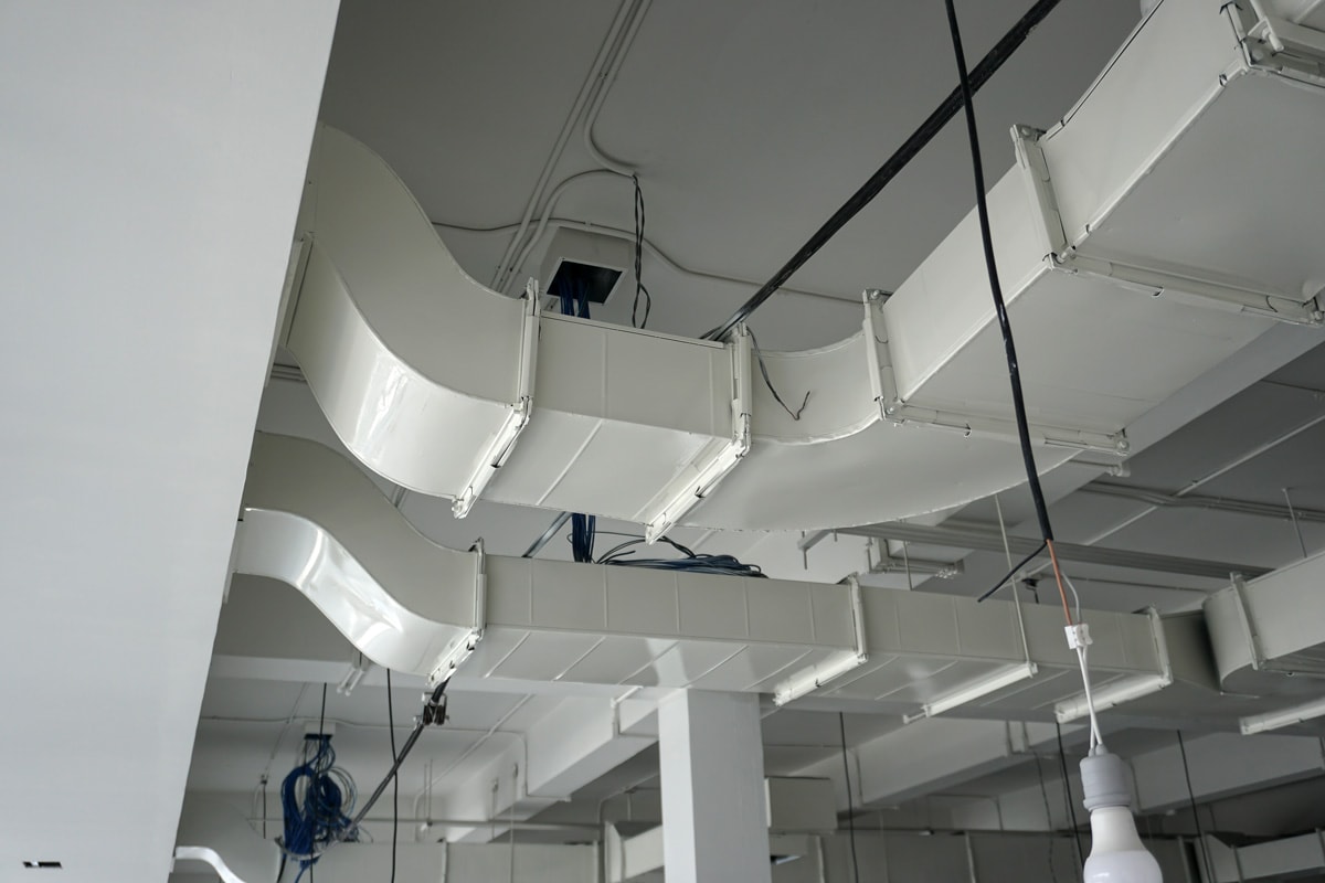 Visible ductwork on the ceiling of a builiding painted in white to avoid rusting
