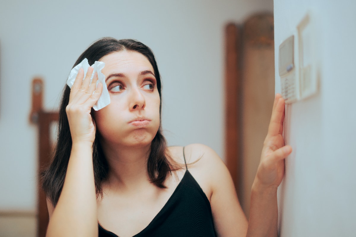 Woman felling hot during summer setting her thermostat
