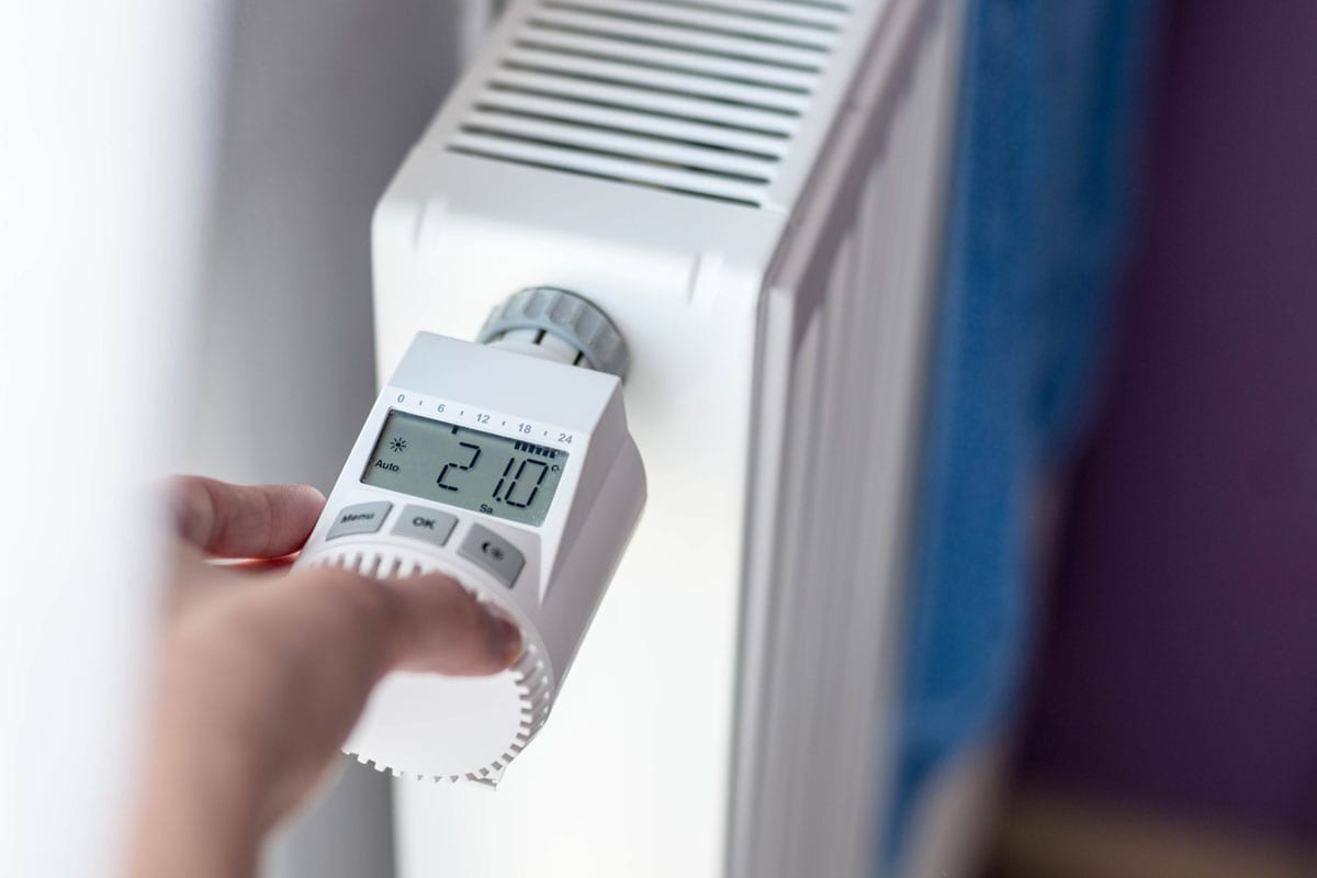 Woman's hand adjusting temperature on home wall heater