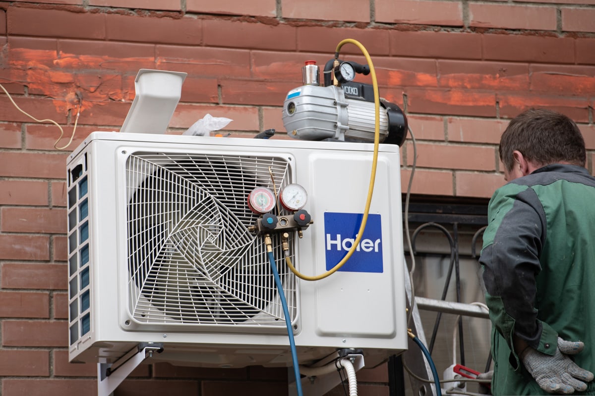 Worker refilling air conditioning system with refrigerant