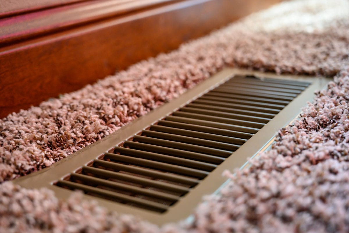 close up photo of an air vent on the brown carpet on the bedroom floor