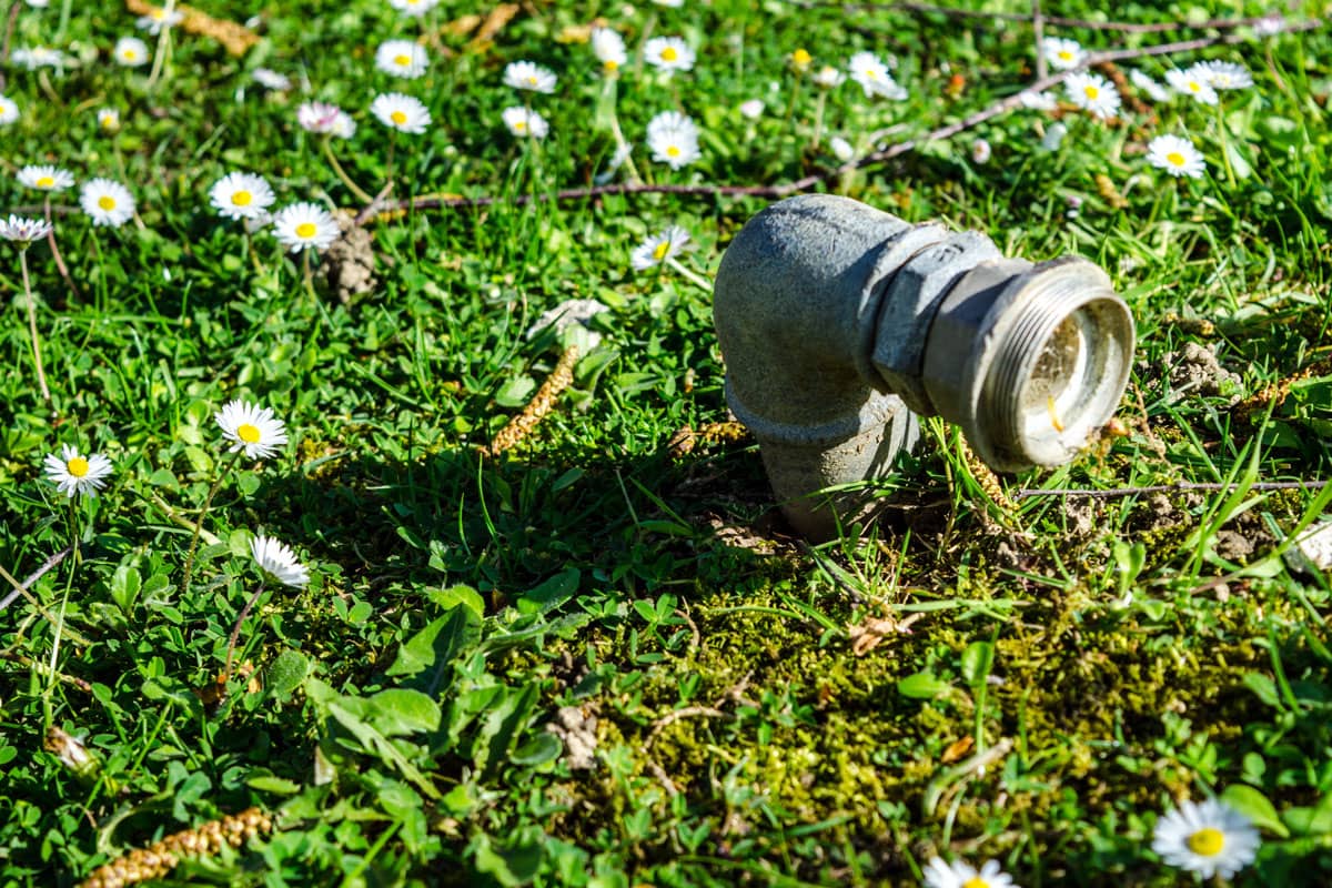 photo of a faucet metal pipe 90 degree elbow pipe on the ground on the grass