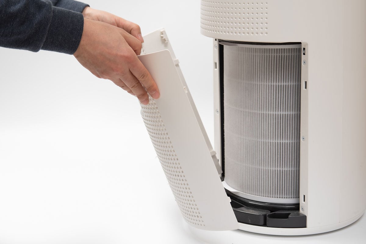 photo of a man opening an air purifier air filter cover replacing air filter