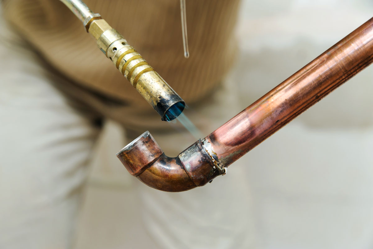 photo of a man soldering a copper pipe fixing pipe broken need new one