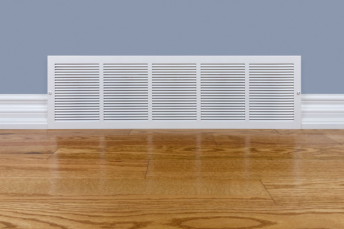 photo of a white style vents for furnace on a wood tile floor and light blue wall