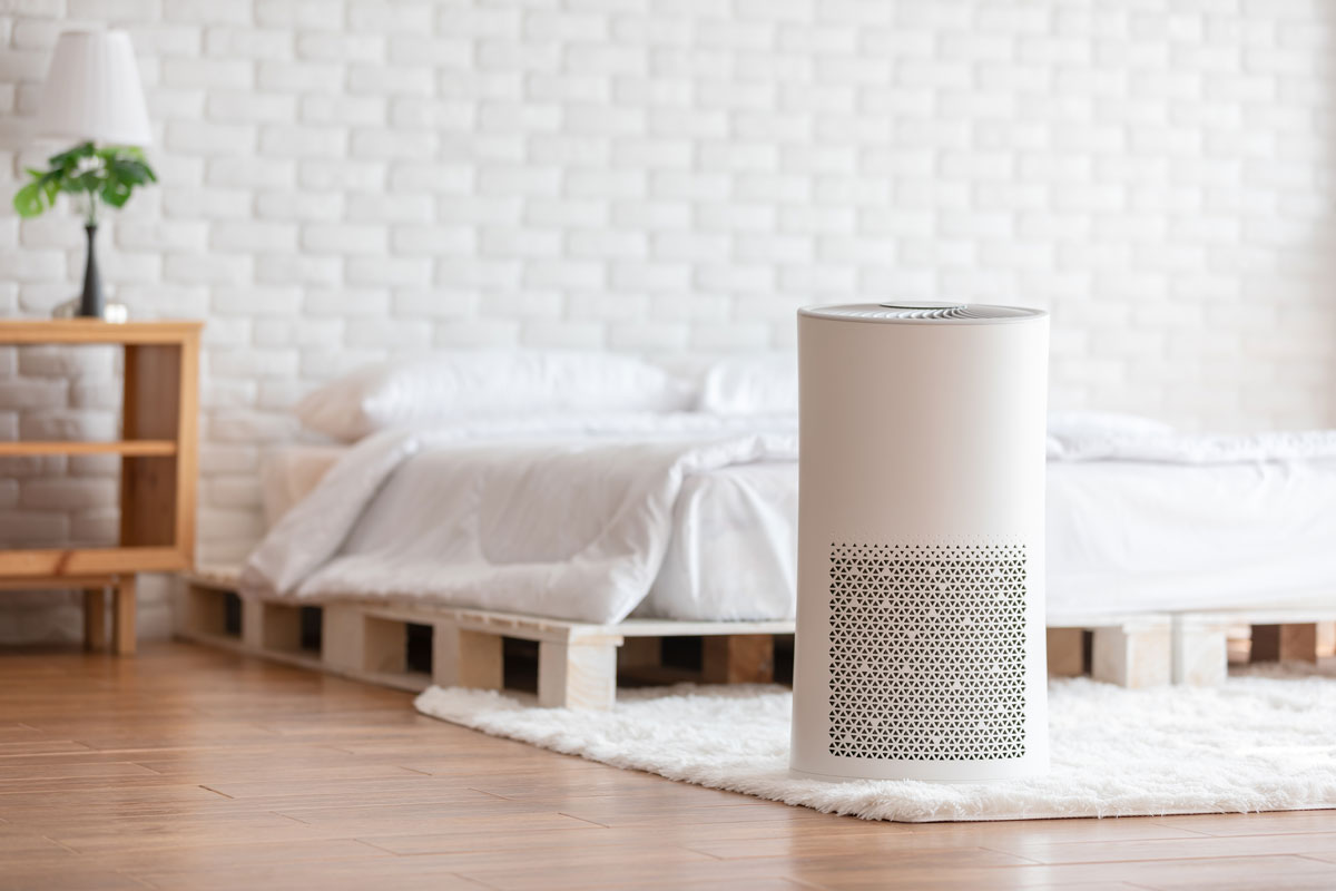 photo of an air purifier inside a clean neat white bed room wood floor tiles