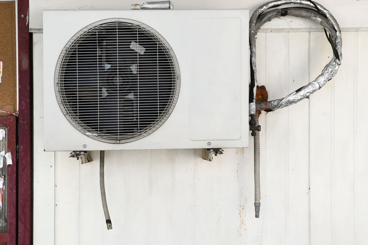 photo of an aircon exhaust fan mounted on a white wall outside the house