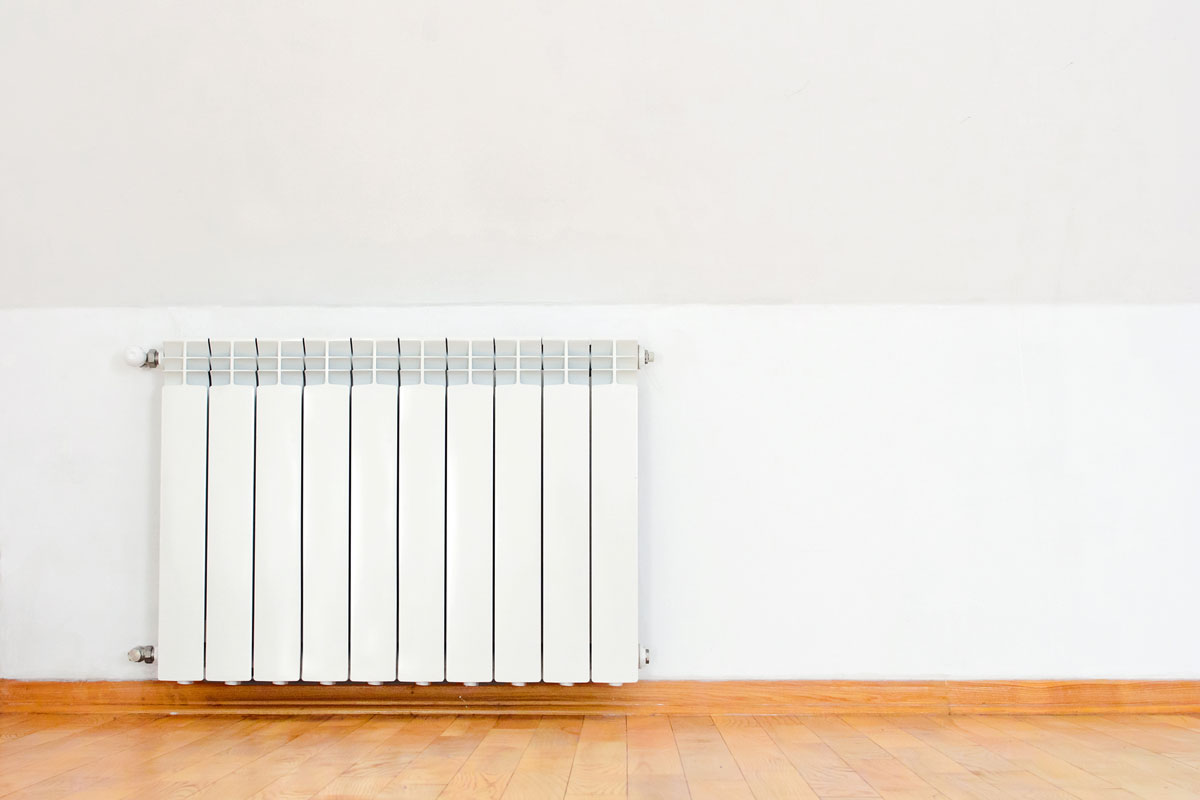white heating radiator on wall and wooden floor