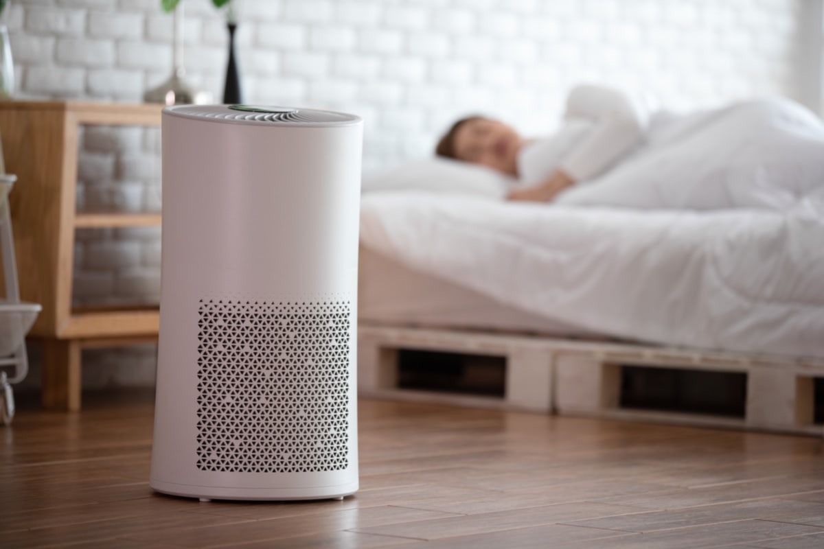 woman sleep with Air purifier in cozy white bed room , Should I Sleep With Air Purifier On