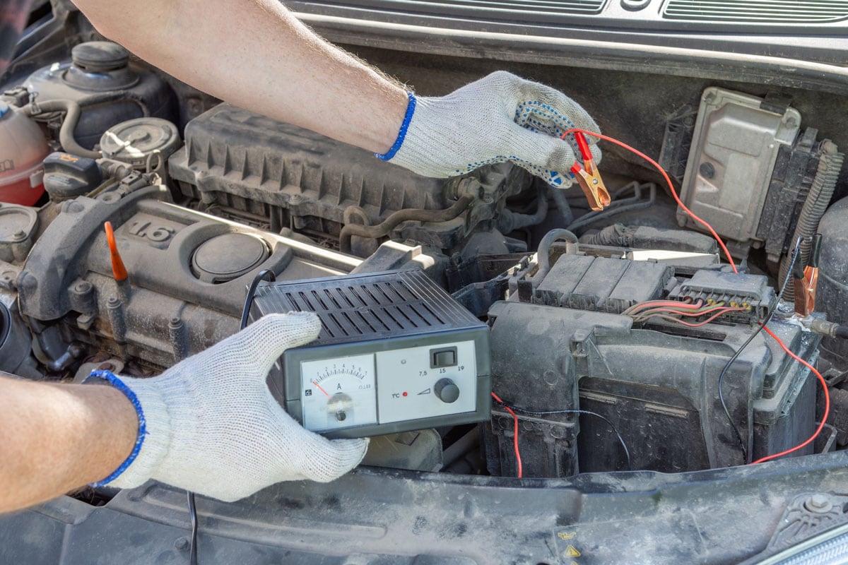 A closeup of a mechanics hands using jumper cables on a car battery