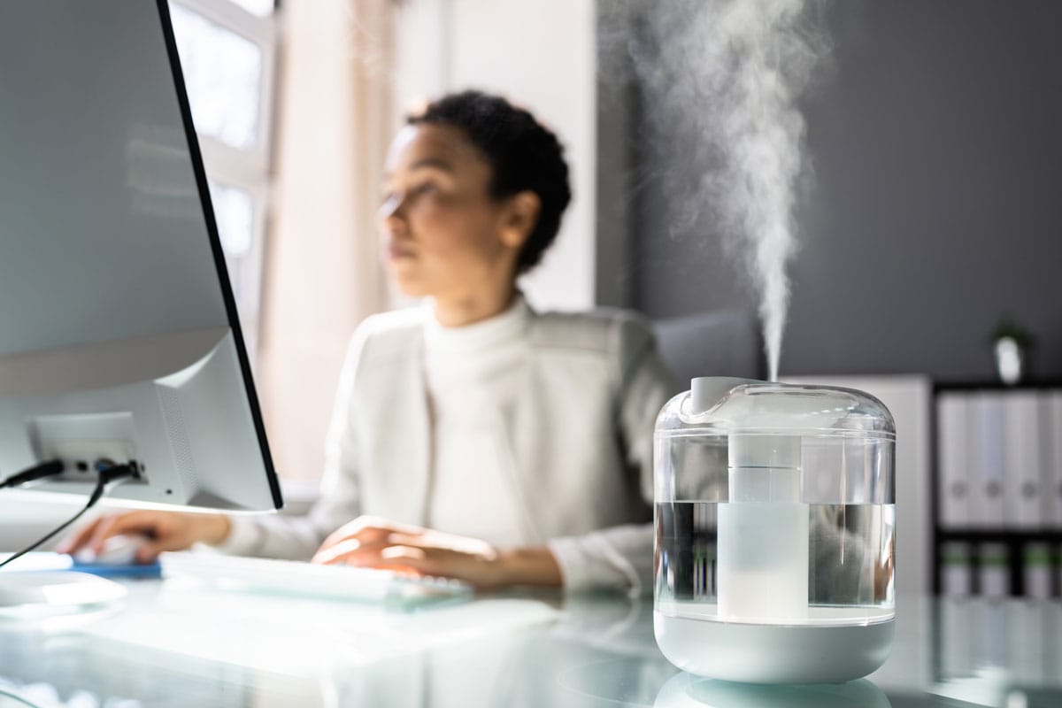 African American Woman In Office with a transparent humidifier