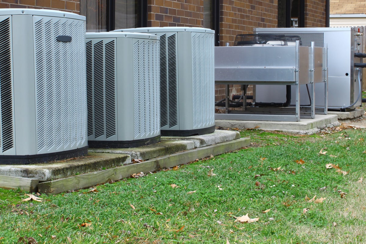 Air conditioning units mounted on concrete blocks and an aiir handler on the back