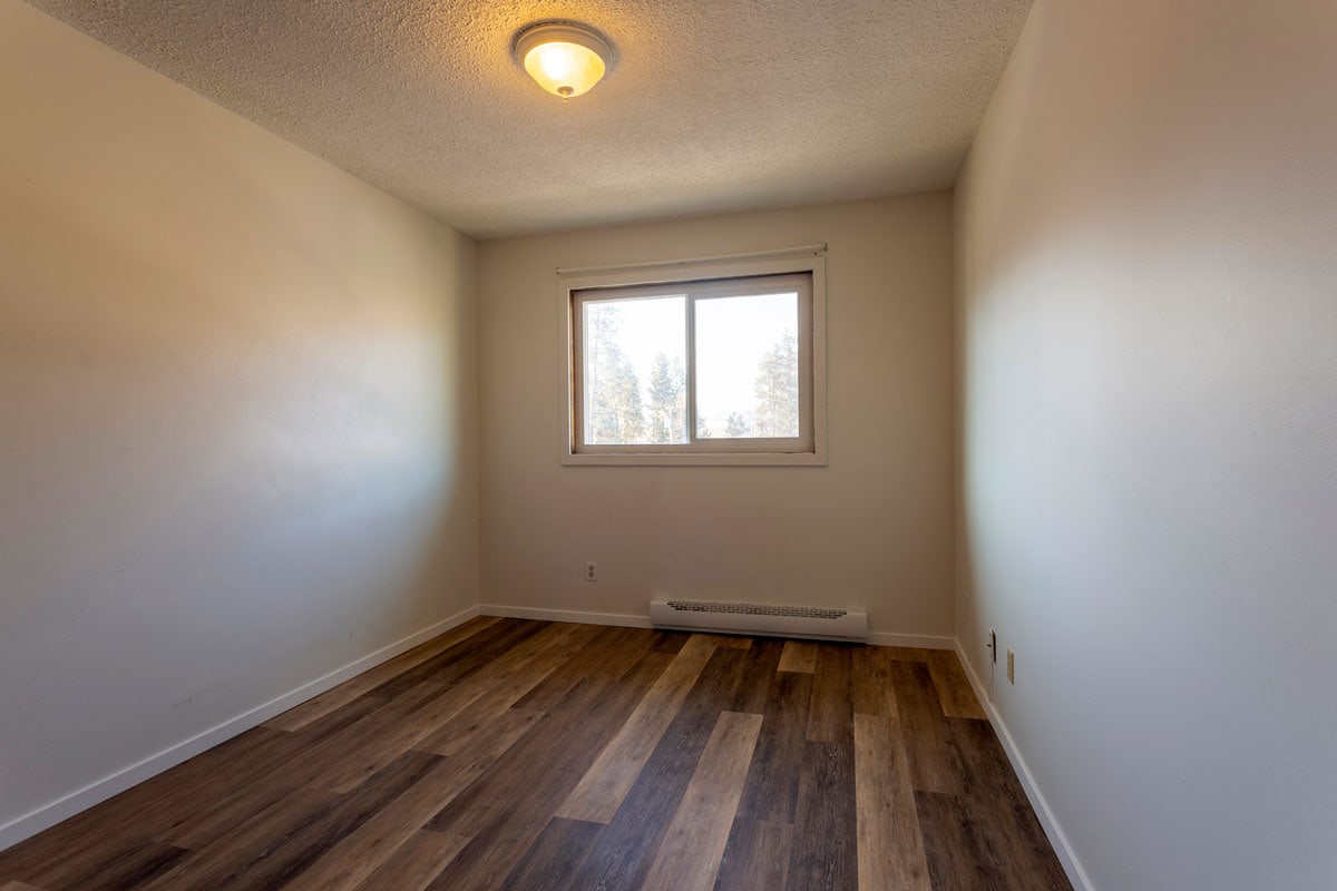 An empty vacant room apartment type property with new hardwood laminate floors and white paint on the walls