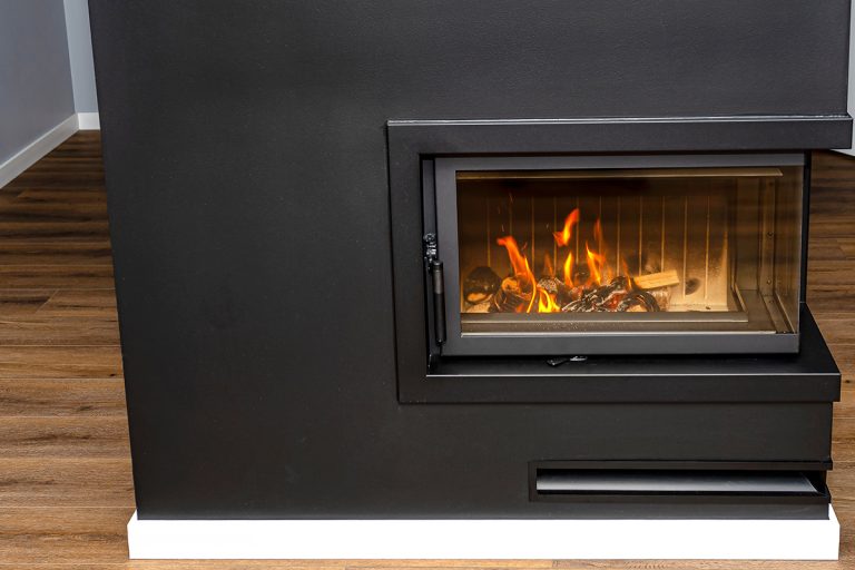 Burning wood in a modern fireplace with a closed combustion chamber, Is Black Soot From Gas Fireplace Dangerous? [What Homeowners Need To Know!]