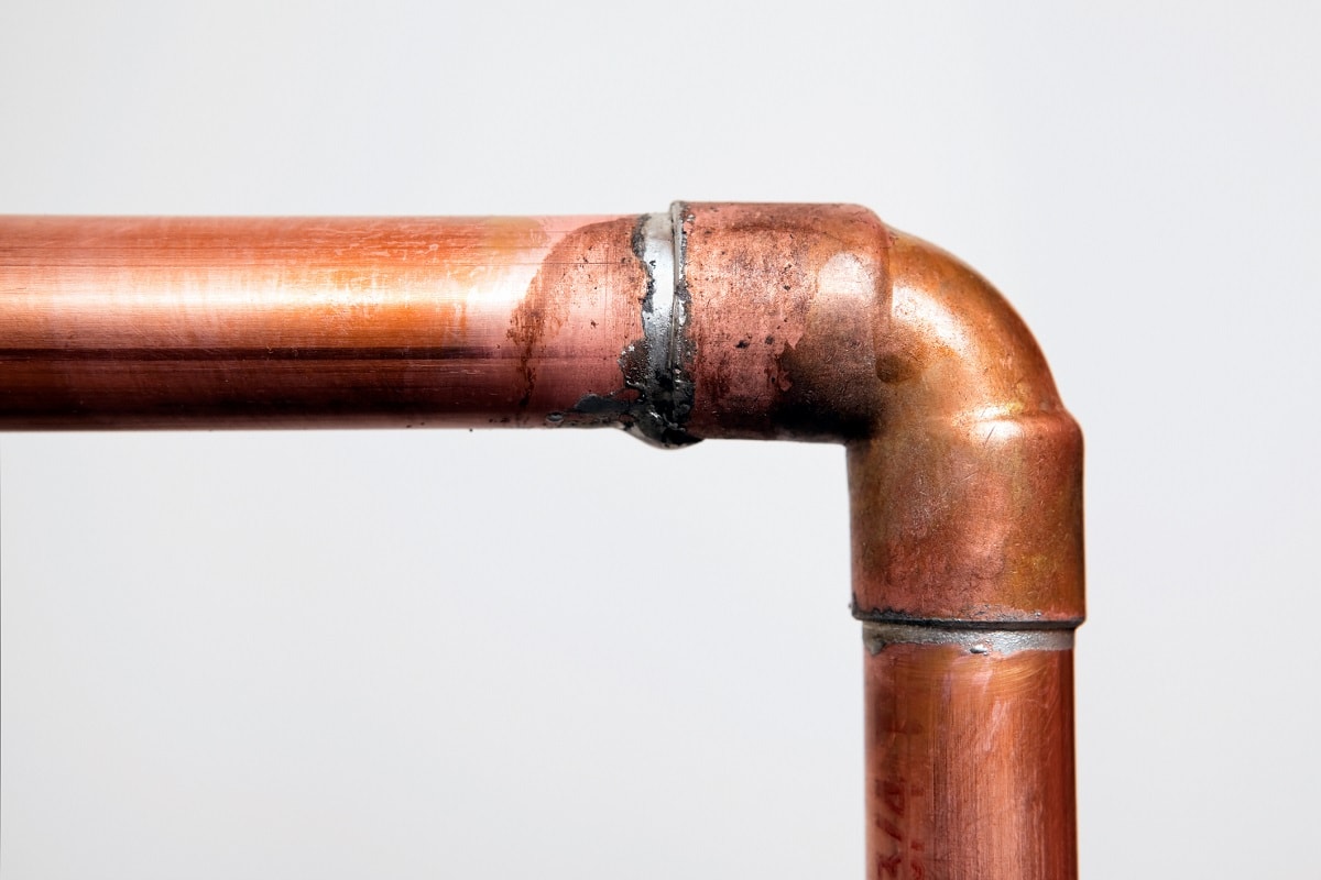 Can You Connect Non-Threaded Galvanized Pipes And Copper Pipes? - Two copper water pipes joined with a 45 degree elbow.