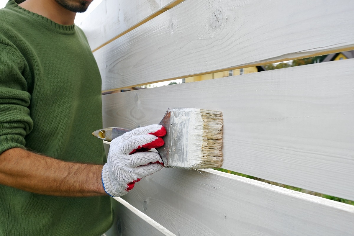 Can You Use Drylok On Wood - Close-up of man painting with brush wooden fence on white color, after winter.