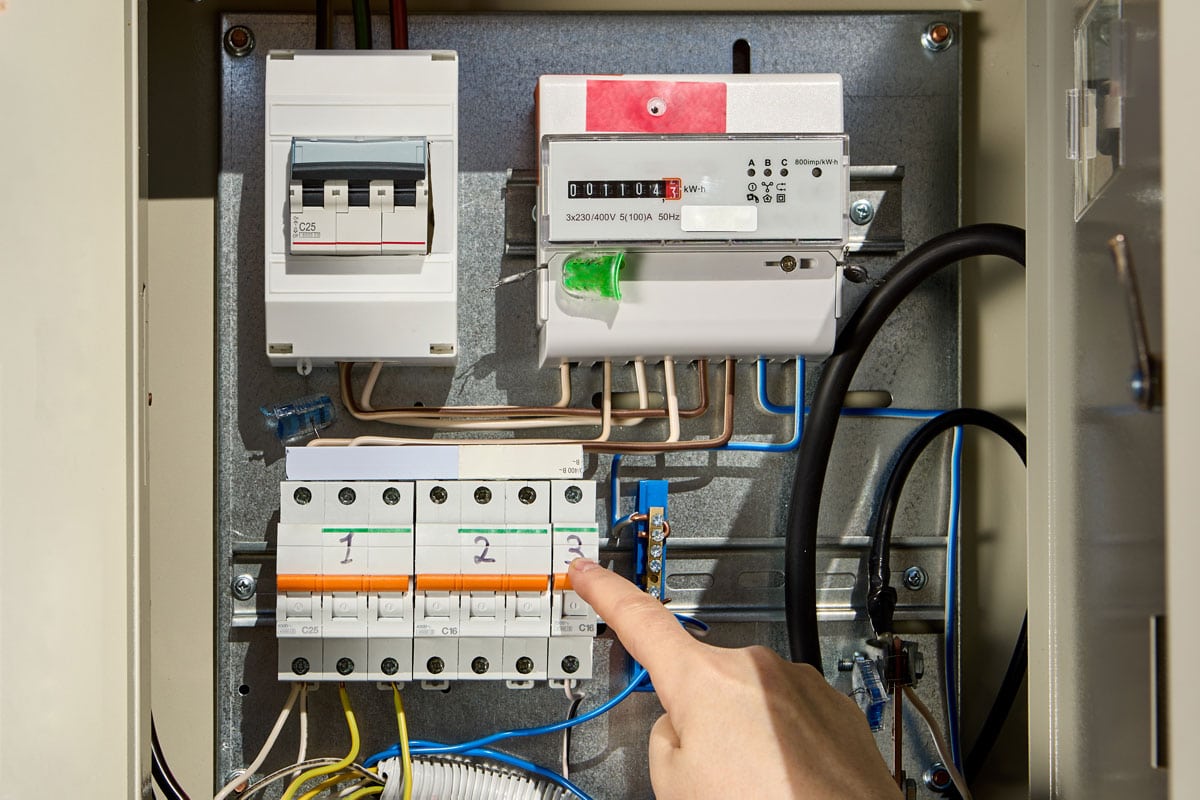 Electrician switches circuit breaker in consumer unit of fuse box and electric meter