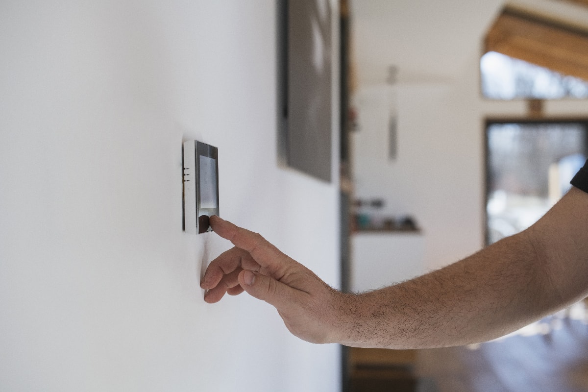 Man at home adjusting thermostat with device on the wall