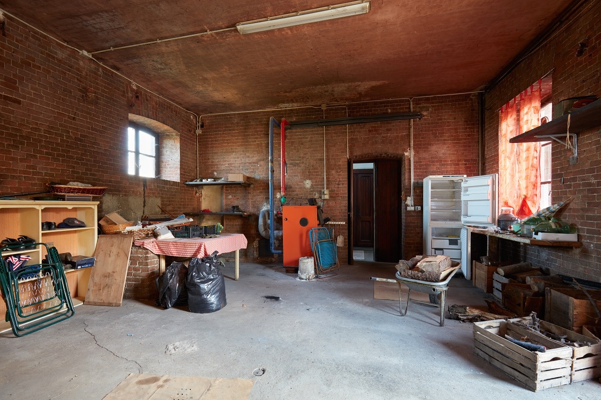 Messy basement with red bricks walls in old country house, What Is The Ideal Basement Humidity? [Inc. In Summer & Winter]