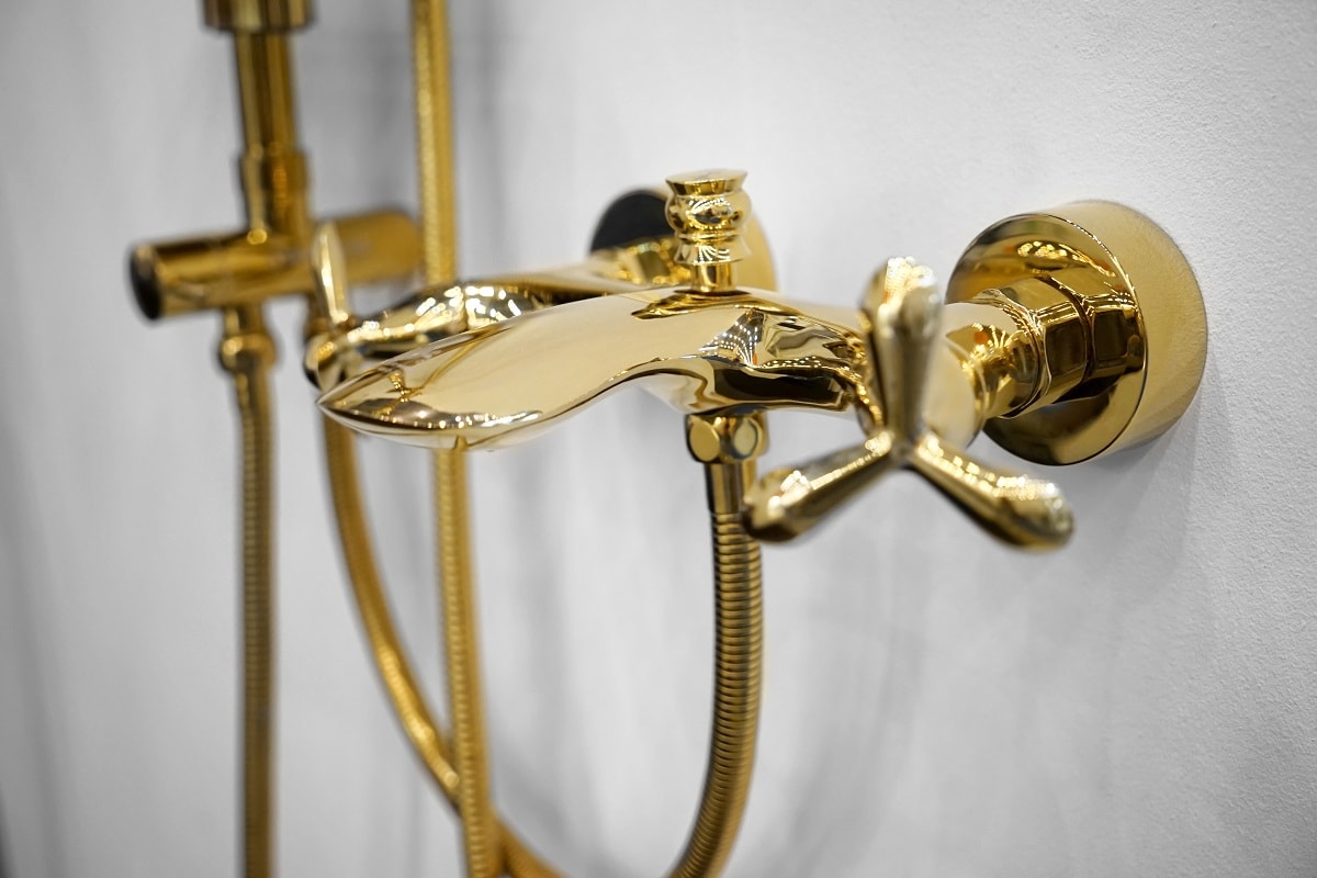 New golden shower faucet on wall, closeup