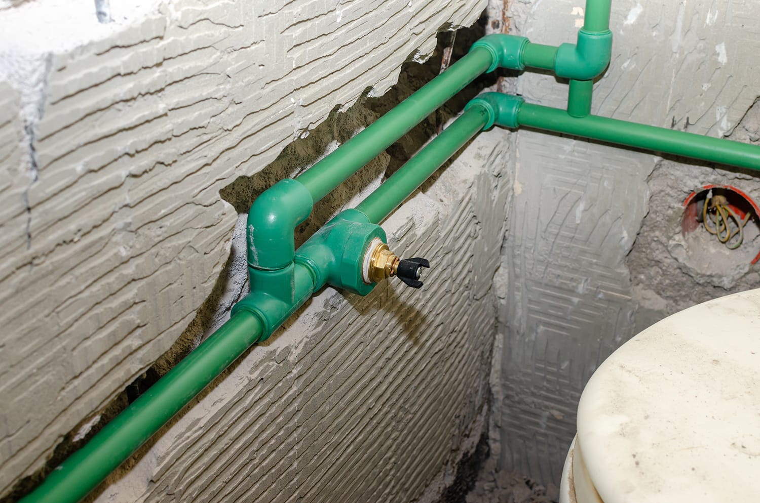 New plastic water pipes installed in a chased bathroom wall during renovation works