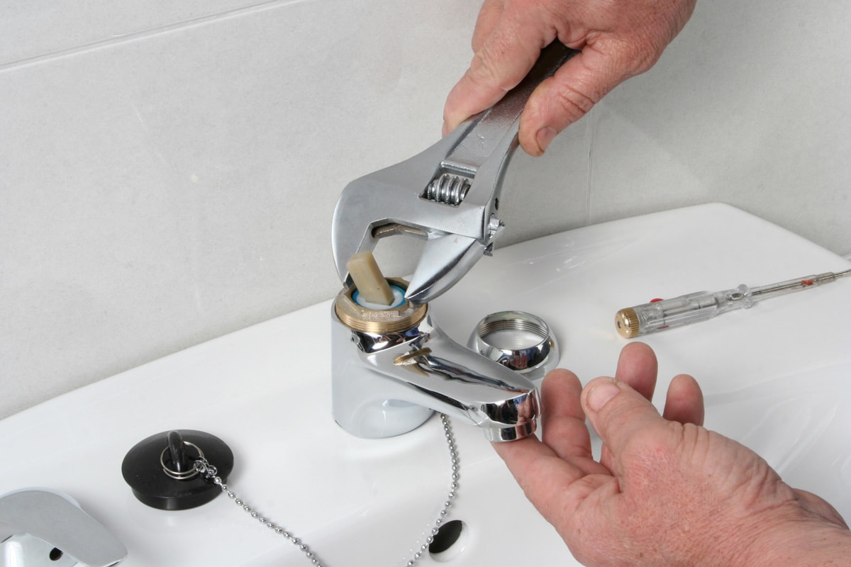 Plumber repairing the faucet of a sink.
