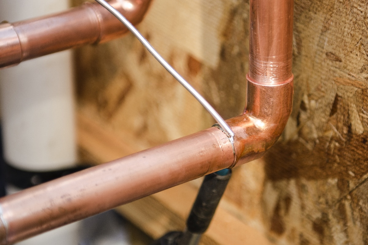 A plumbing contractor sweating the joints on the copper pipe