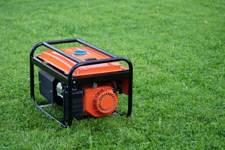 Portable electric generator on the green grass outdoor, Why Is My Generator Blowing Smoke? [Inc. White, Blue, & Black]