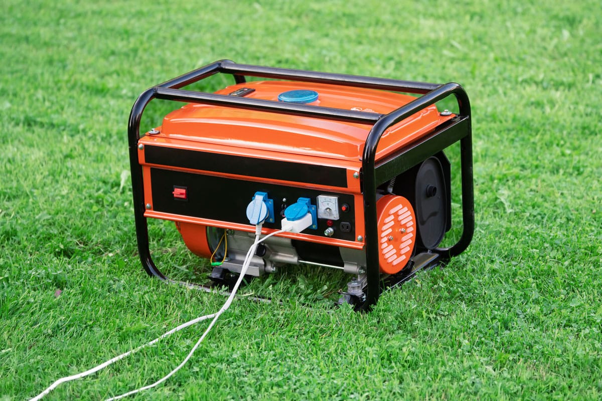 Portable electric generator with electric wires connected on the green grass in summer