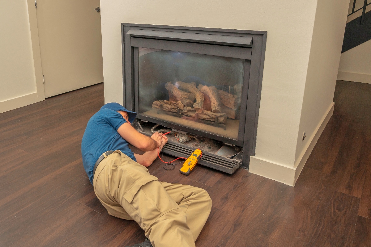 Service technician working on a gas fireplace inside of a residential home