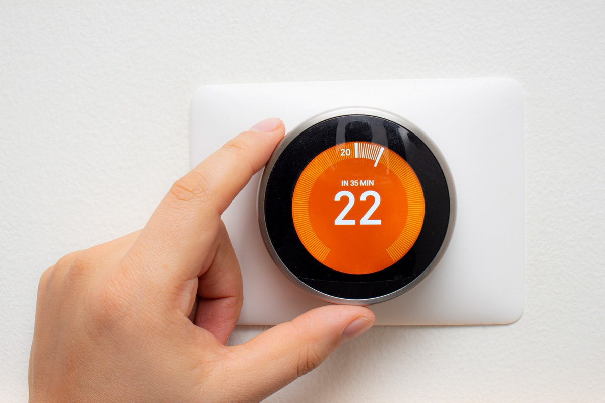 Smart Thermostat with a person warming up the room temperature with a soft shadow.