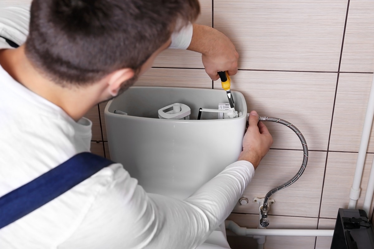 There is inadequate air pressure or air drawn in the tank - Plumber repairing toilet cistern at water closet