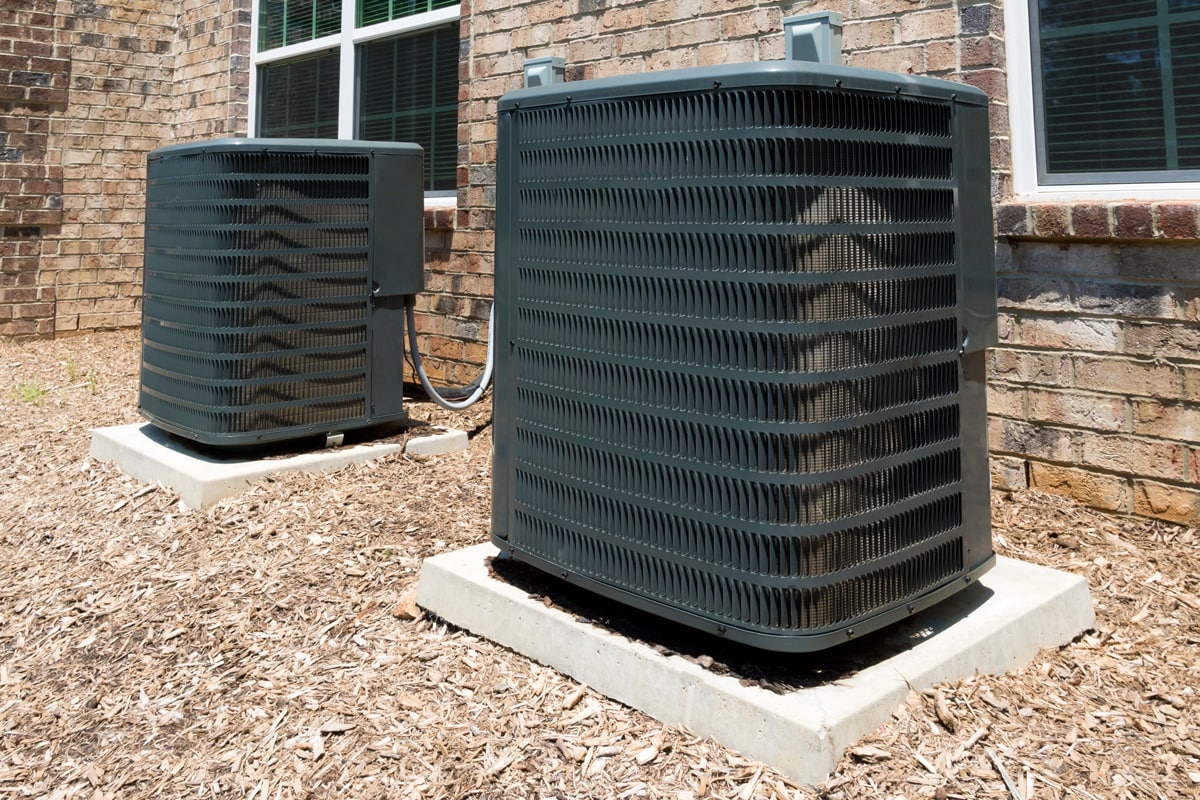 Two huge black air conditioning units mounted on concrete pads